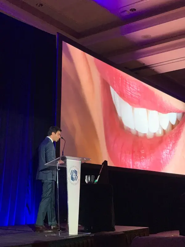 Ponente en un congreso ante una proyección de una sonrisa