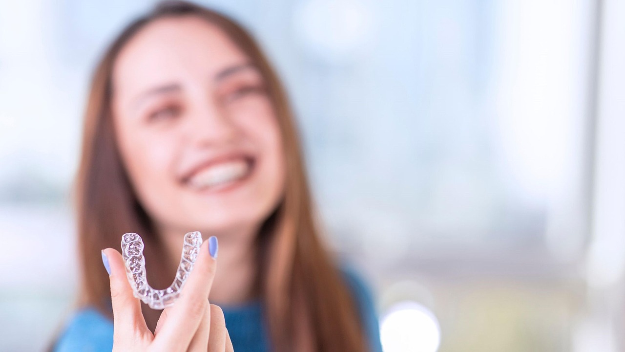 Mujer sonriente sosteniendo un alineador transparente